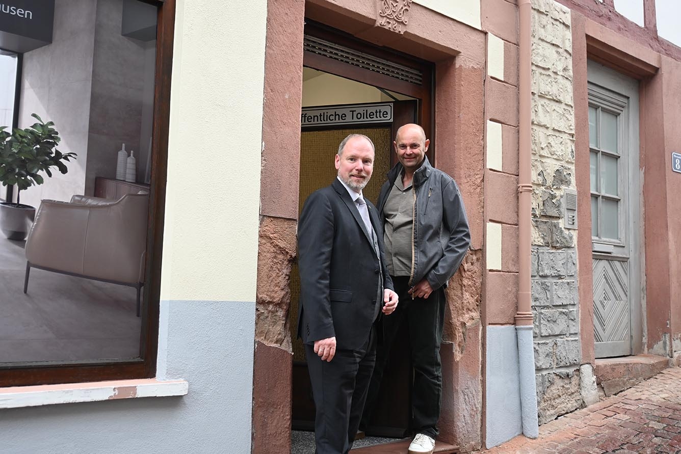 Bürgermeister Christian Litzinger und Projektleiter Thorsten Amend stehen im Eingang der neuen öffentlichen Toilette an der Kuhgasse.