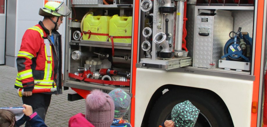 Kinder stehen vor einem Feuerwehrauto.