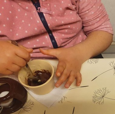 Kinderbetreuung Schokoprojekt in der Kita Rappelkiste: Ein Kind rührt Schokolade in einer Tasse.