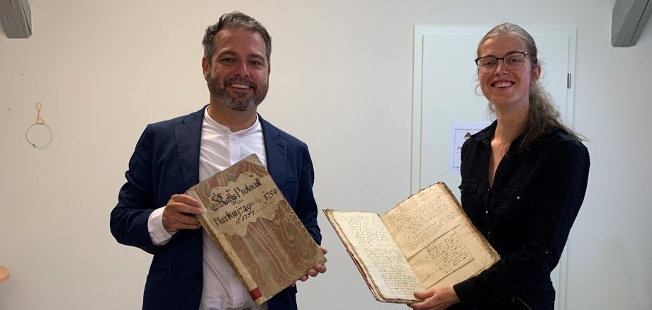 Bürgermeister Glöckner und die wissenschaftliche Mitarbeiterin Hanna Nüllen präsentieren die Stadtbücher, die nun online gefunden werden können.