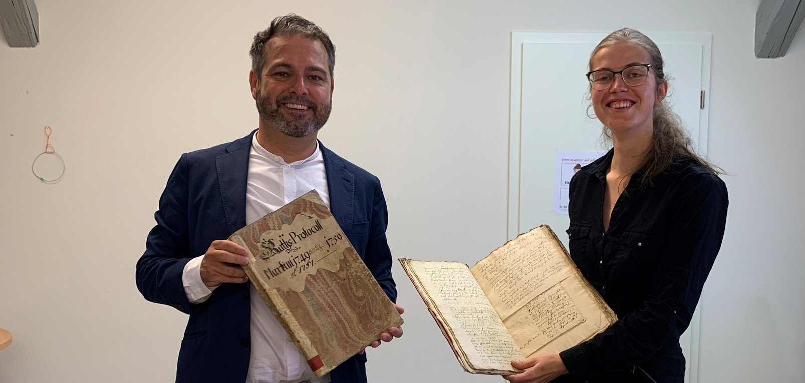 Bürgermeister Glöckner und die wissenschaftliche Mitarbeiterin Hanna Nüllen präsentieren die Stadtbücher, die nun online gefunden werden können.