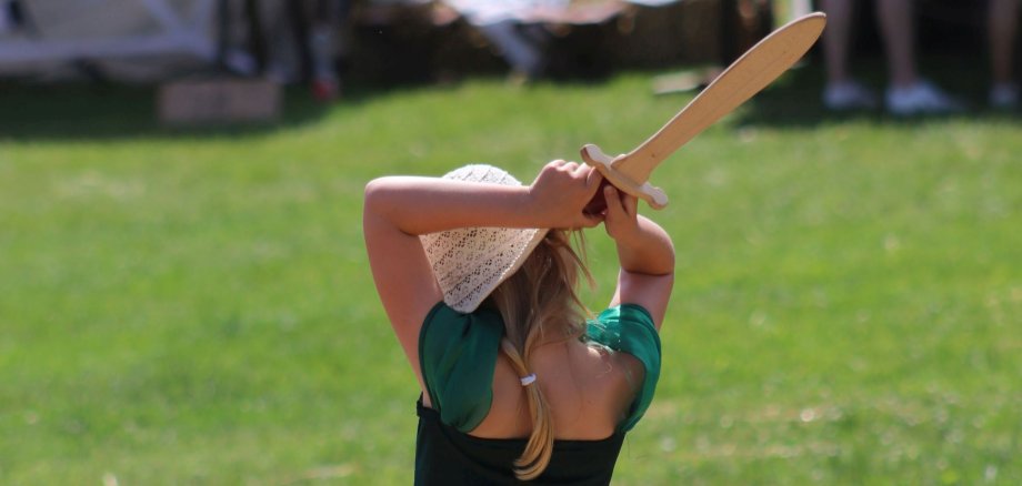 Ein Mädchen schwingt ein Holzschwert.