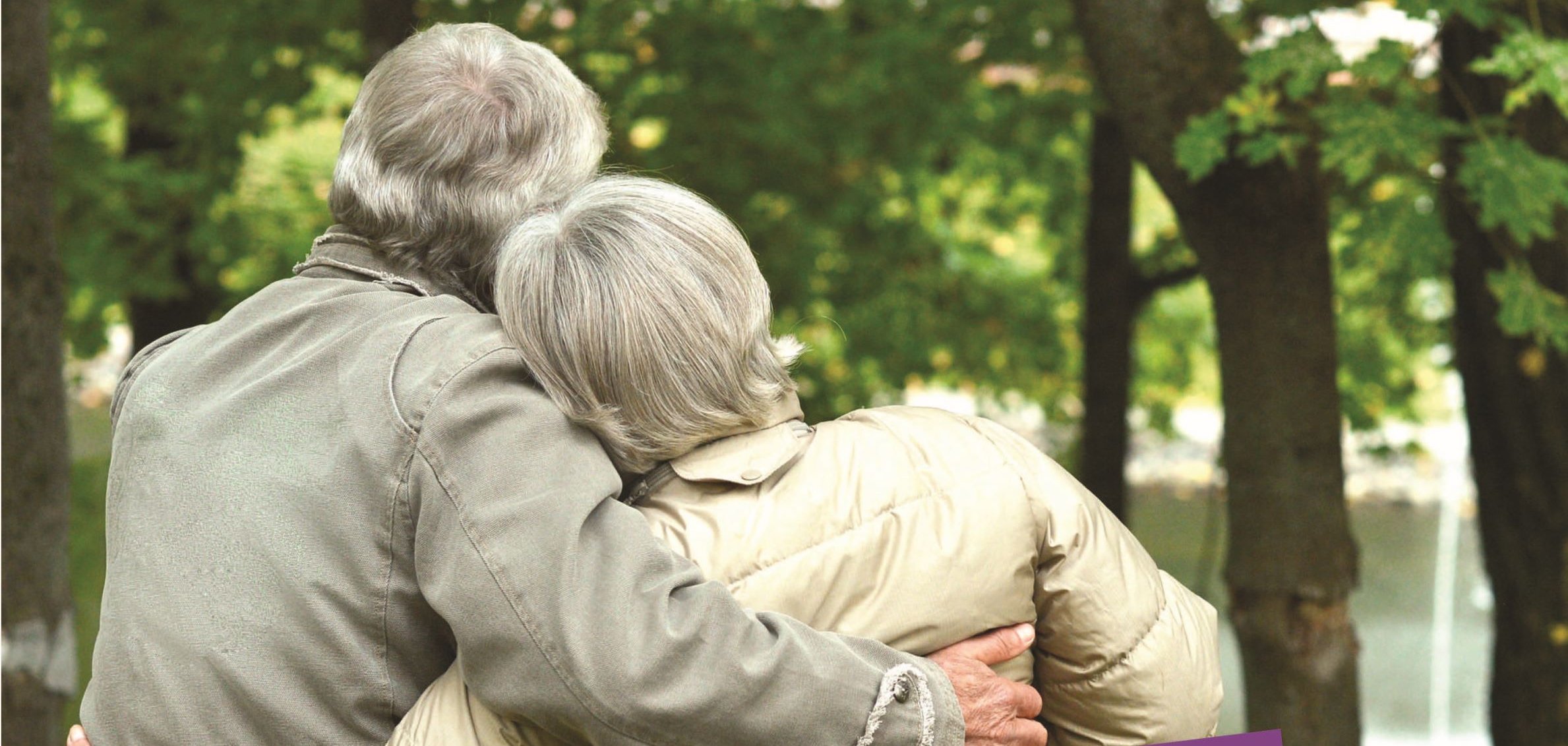 Plakat zum Weltalzheimertag. Ein älteres Paar sitzt auf einer Bank und umarmt sich. 