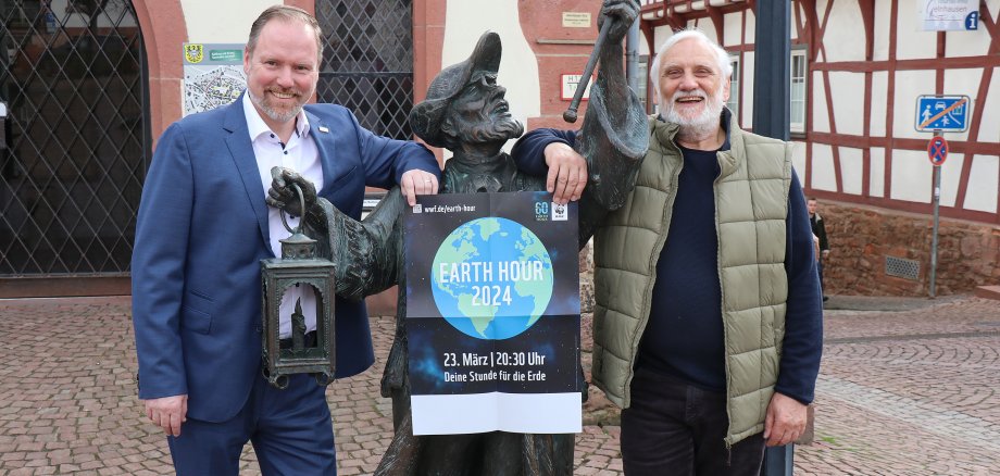 Bürgermeister und Stadtrat mit dem Earth-Hour-Plakat an der Nachtwächter-Figur vor dem Rathaus. 