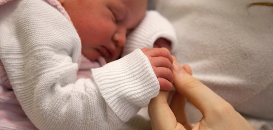 Die Hand einer Frau hält die Hand eines Babys.