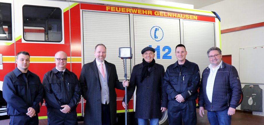 Feuerwehraktive, Bürgermeister und Versicherungsvertreter  mit dem neuen LED-Beleuchtungssystem vor einem Feuerwehrfahrzeug.