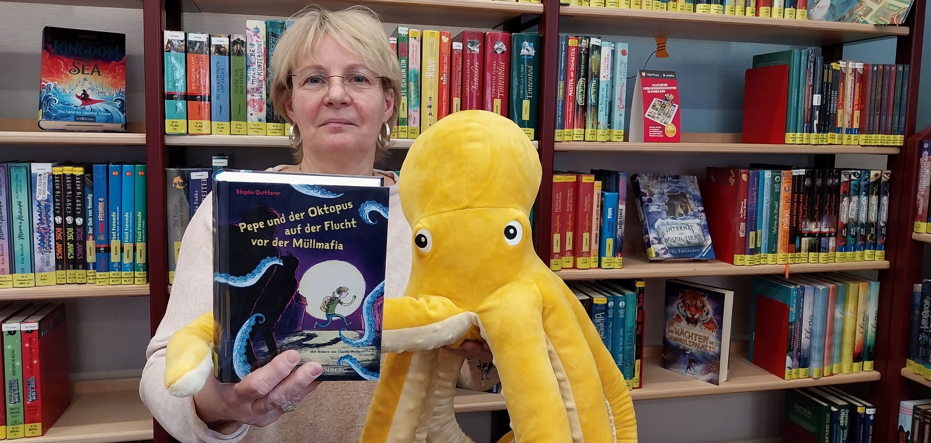 Büchereileiterin Claudia Beck mit Buch und Plüsch-Oktopus.