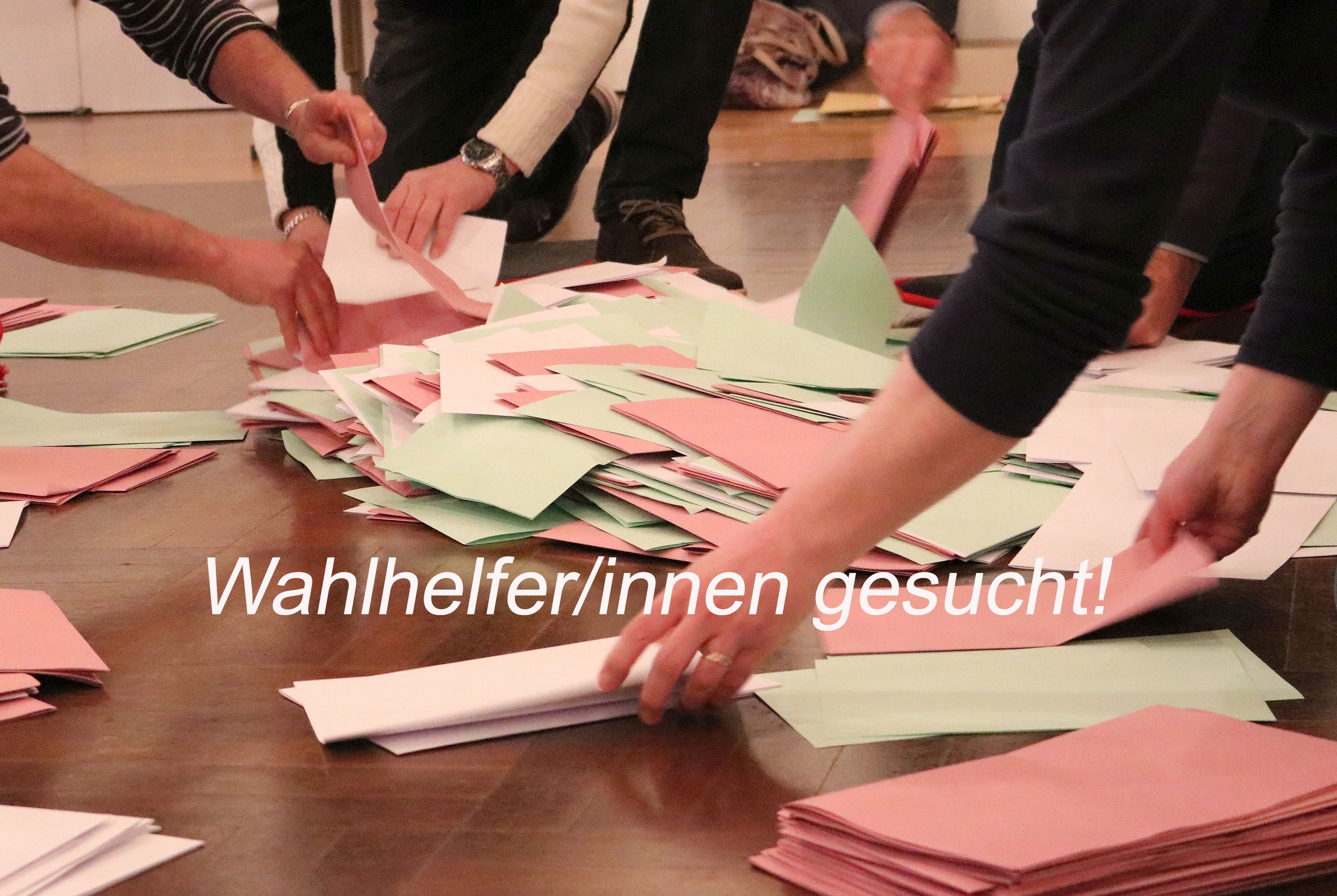 Der Bildausschnitt zeigt Hände, die verschiedenfarbige Wahlzettel sortieren.