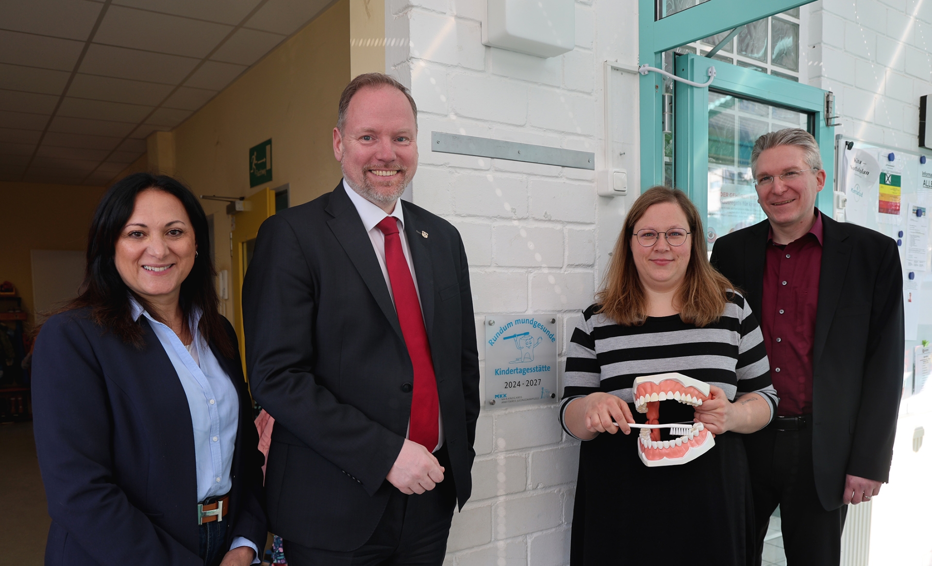 Die Gruppe mit einem überdimensionalen Gebiss vor dem Zertifikat.