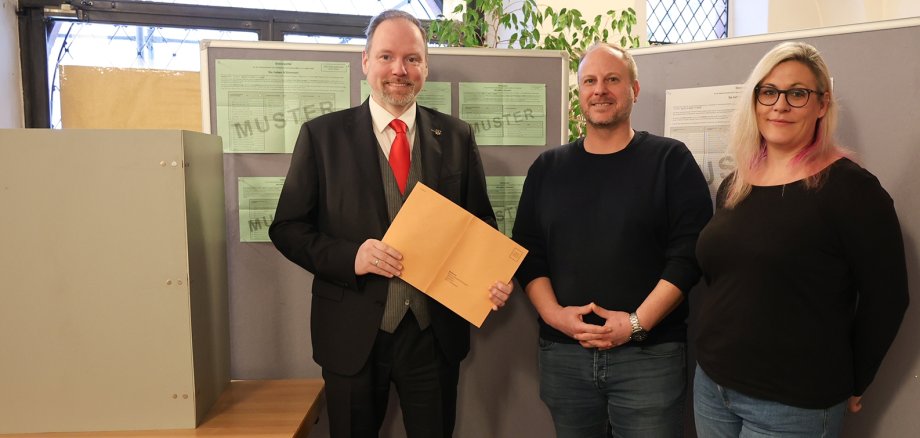 Aufruf Stimmabgabe Der Bürgermeister und das Wahlamt vor den Musterstimmzetteln im Rathausfoyer.