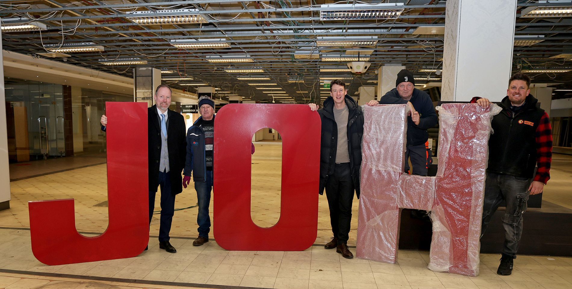 Gruppenbild mit dem Schriftzug JOH, der an der Fassade angebracht war.