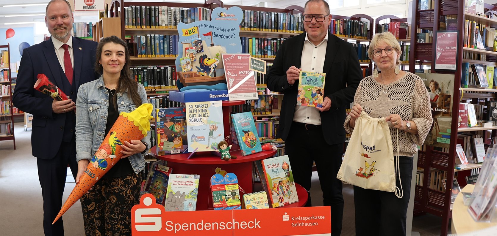 Förderung der Lesekompetenz: Ole Schön, Vorstandsvorsitzender der Kreissparkasse Gelnhausen (rechts), übergibt eine Spende in Höhe von 500 Euro an Bürgermeister Christian Litzinger (links), Bücherei-Leitung Claudia Beck (vorne rechts) und Bücherei-Mitarbeiterin Lisa Lapp (vorne links).  