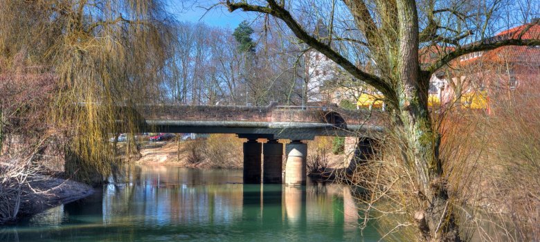 Seitenansicht auf die Brücke bei der Müllerwiese. Rechts im Bild sieht man einen Baum im Vordergrund am Ufer.
