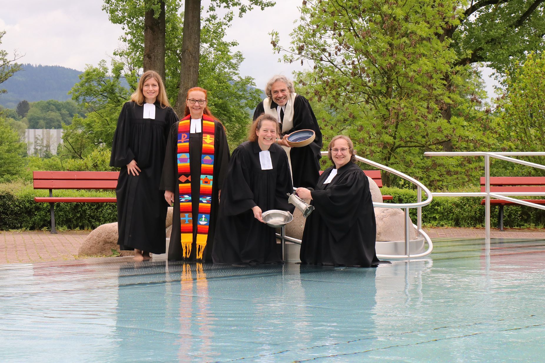 Vier Pfarrerinnen und ein Pfarrer in Talaren im Nicht-Schwimmerbecken.