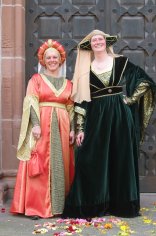 Bandeley 2 festlich gekleidete Gästeführerinnen in Kostümen aus der Zeit der Patrizier. Die Kleider sind aus roter Seide und dunkelgrünem Samt.