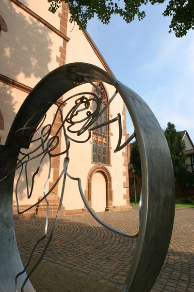 Henker, Hexen, Heimlichkeiten Eine moderne Skulptur aus schwarzem Metall erinnert an eine Frauengestalt in Erinnerung an die Hexenverfolgung. Im Hintergrund die Fassade der Marienkirche.