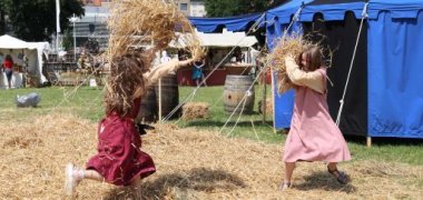 Kinder in mittelalterlicher Kleidung machen eine Strohschlacht