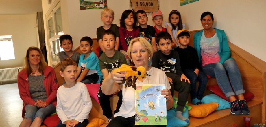 Büchereileiterin Claudia Beck lässt eine Stoffbiene durch den Raum schweben. Hinter ihr sitzen die Kinder der Kita Rappelkiste.