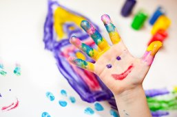 Kleine Kinderhand malt mit Fingerfarben Bild einer kleinen Kinderhand die mit Fingerfarben in verschiedenen Farben malt