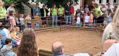 Ein Netz aus Wollfäden wird um Kinder und Eltern gespannt.