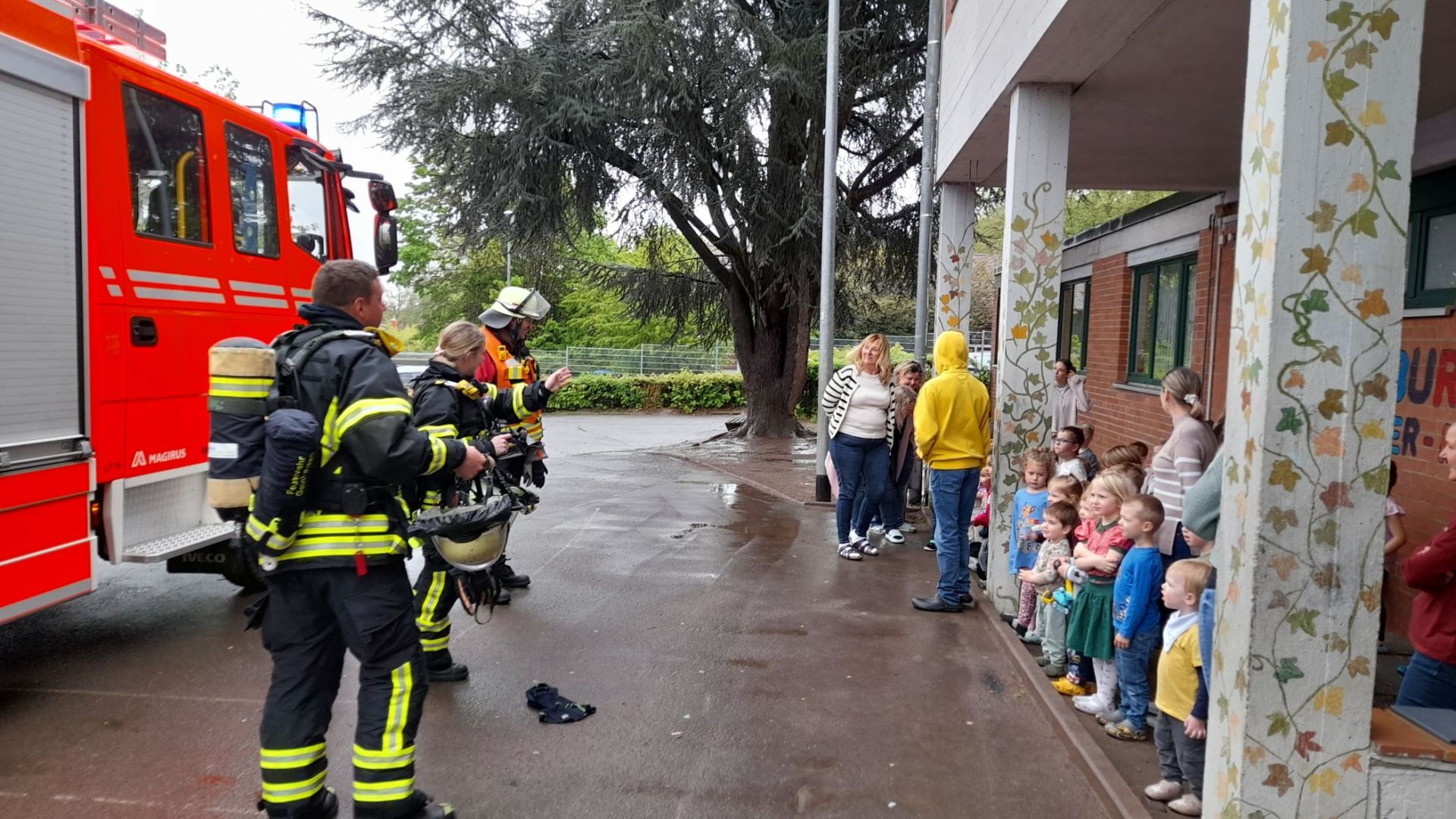 Drei Einsatzkräfte der Feuerwehr geben den Kindern Anweisungen. 