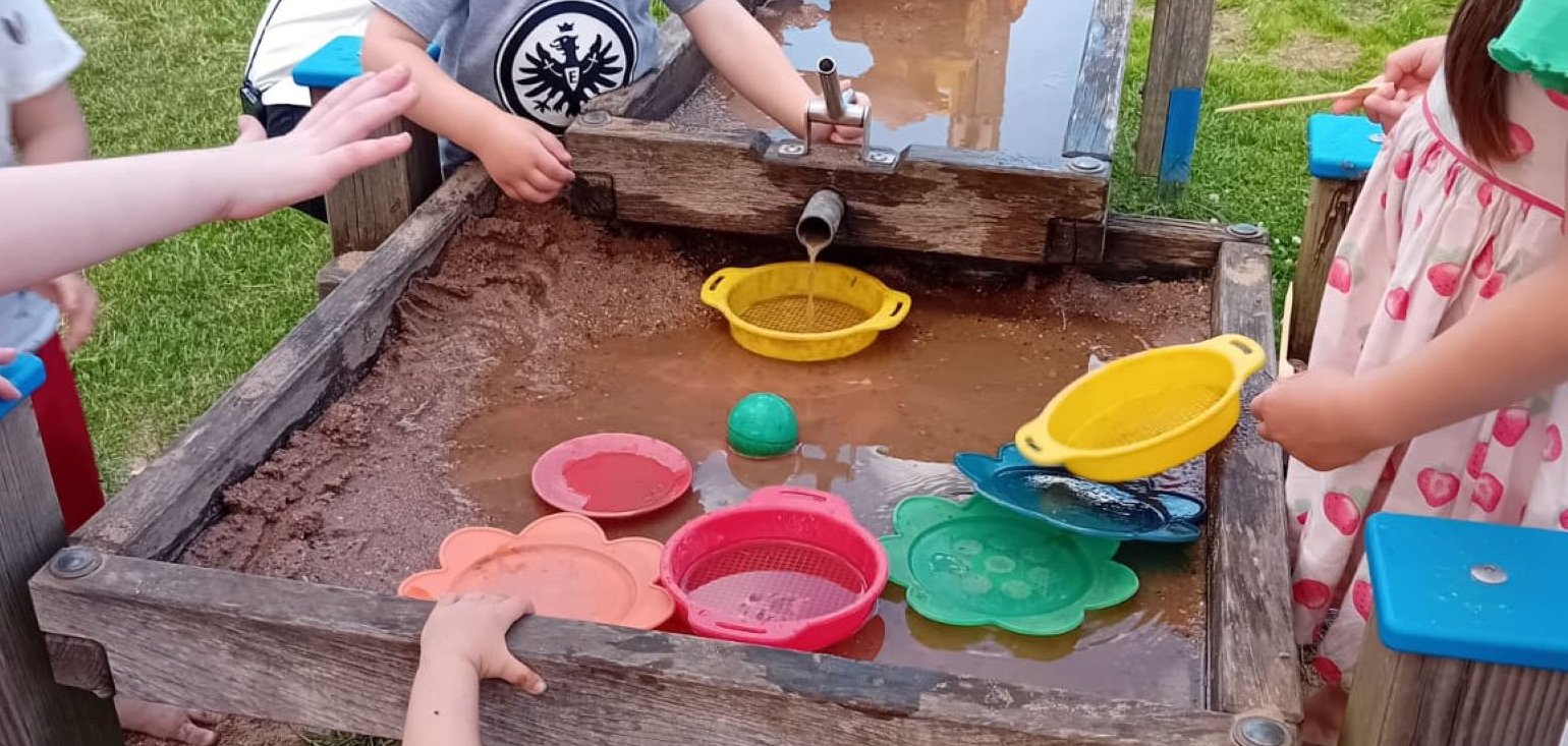 Kinder spielen an der Wasserstelle.