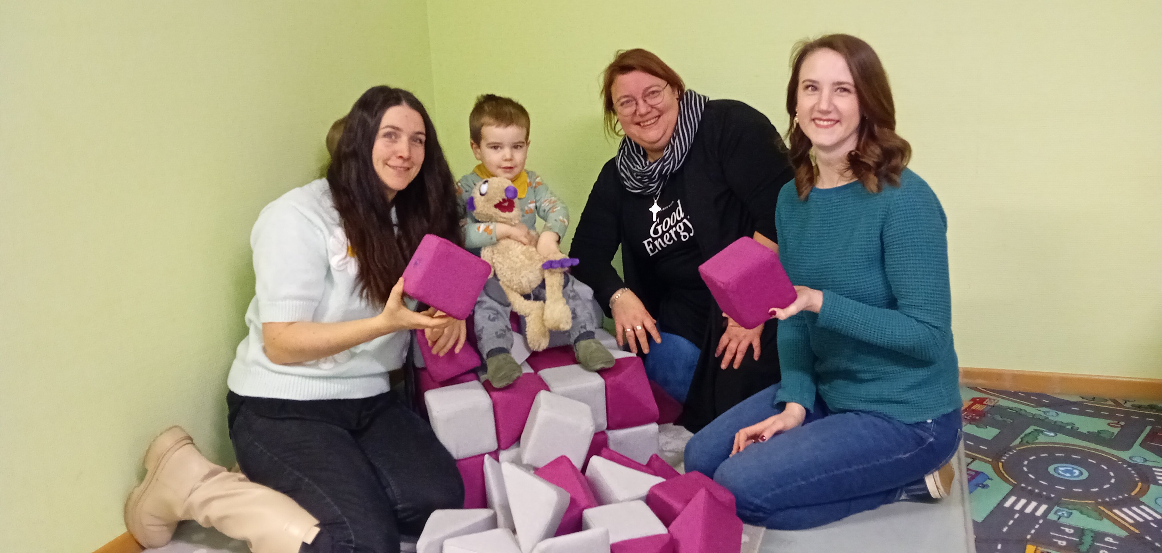 Eine Gruppe Frauen und ein Kleinkind mit den Magnetbausteinen in Pink und Hellgrau.
