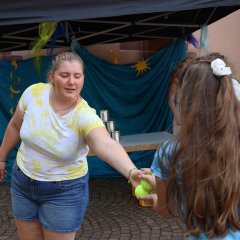 Kindersommer 2026 Eine Teamerin übergibt Wurfbälle an ein Mädchen.
