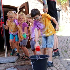 Kinder gegen Erwachsene am Steinbrunnen: Wer füllt in vier Minuten mittels Menschenkette und Trinkbechern das meiste Wasser in einen Eimer?