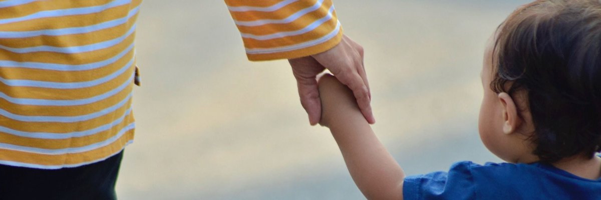 Eine Frau hält ein Kleinkind an der Hand.