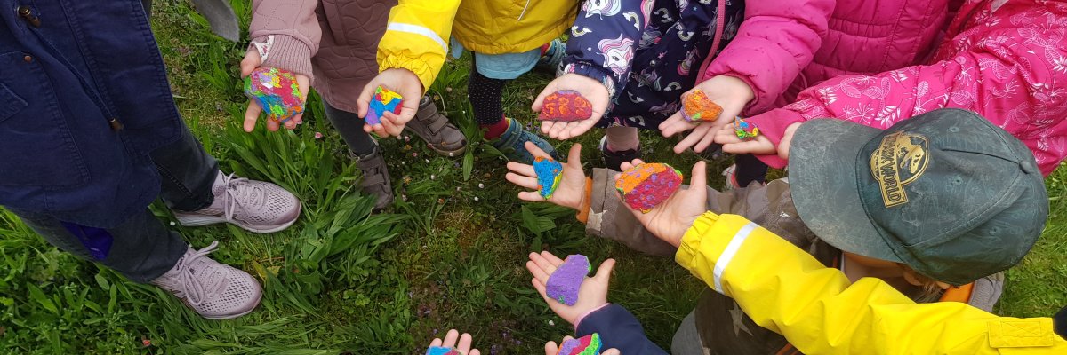 Kinderhände präsentieren bunt bemalte Steine. Projekt der Kita Goethes Kinderwelt.