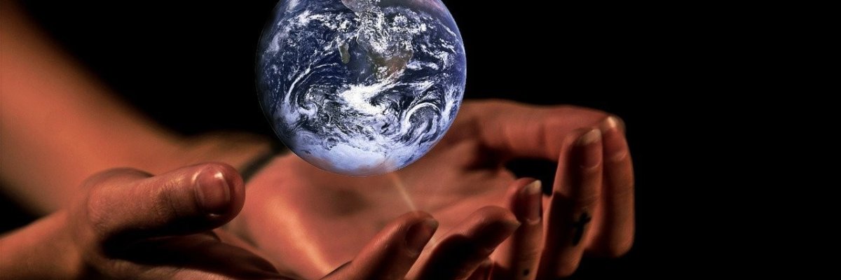 Die Erde schwebt als Miniatur über Frauenhänden.