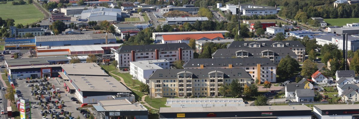 Luftaufnahme. Blick auf den Wohn- und Gewerbepark Colemancenter mit mehrstöckigen Wohngebäuden, Ladenzeilen und Parkflächen.