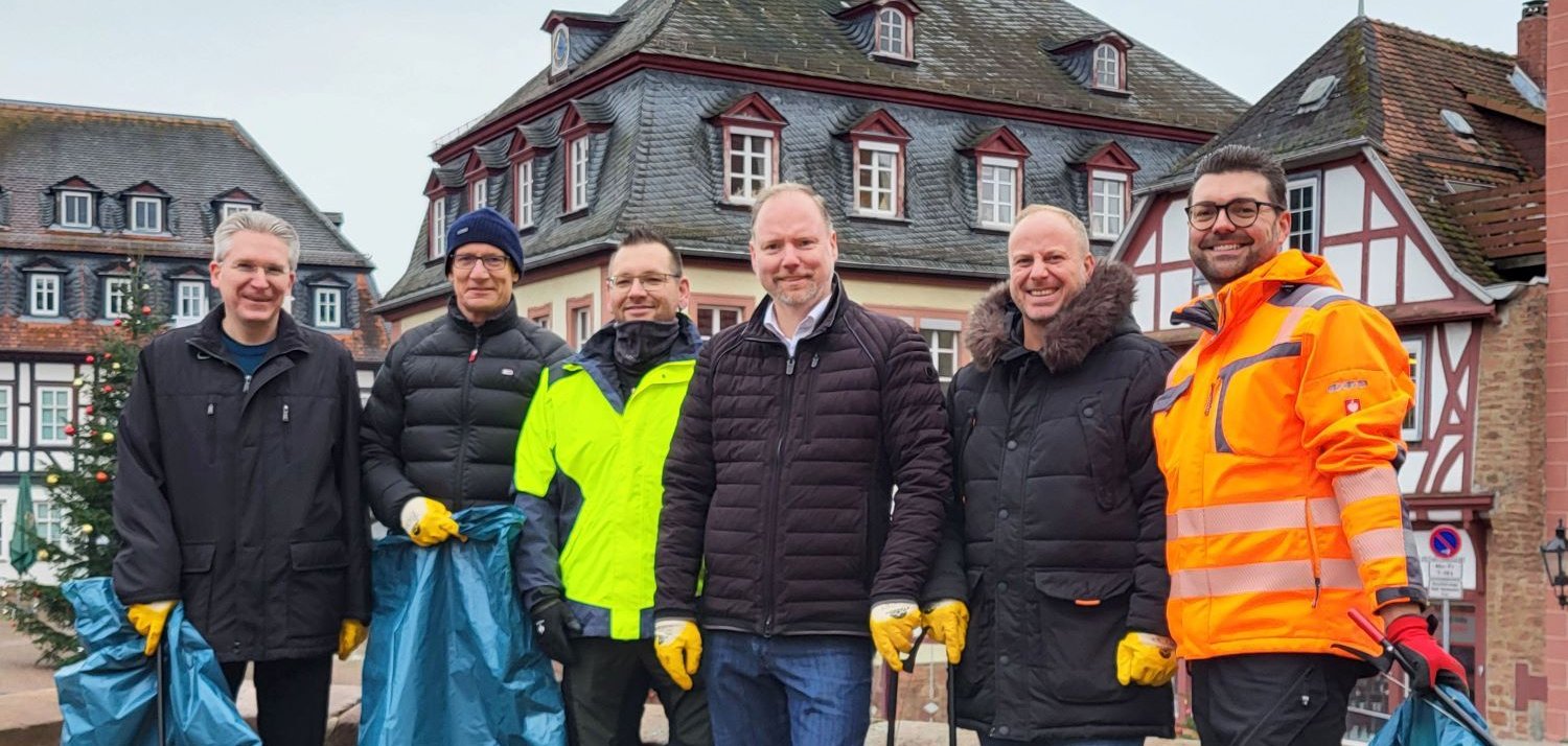 Bürgermeister Christian Litzinger und fünf Mitarbeiter des Rathauses stehen auf dem Obermarkt mit Müllbeuteln und Müllzangen in den Händen vor zusammengesammeltem Müll.