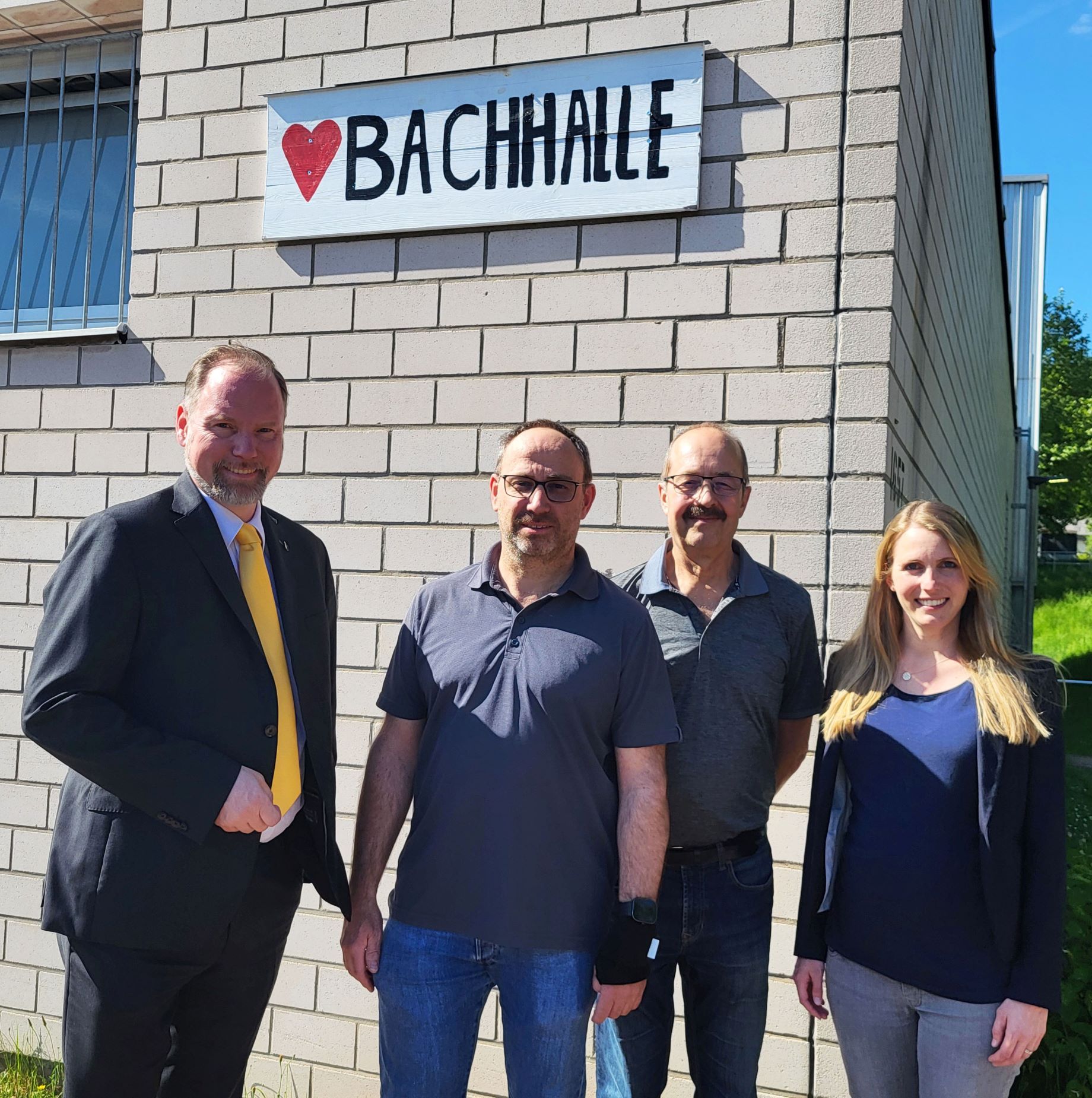 Bürgermeister Christian Litzinger, BCG-Mitglied Christian Böhler, BCG-Vorsitzender Rudolf Düring und Jasmin Düring von der Firma Dorn Malerfachbetrieb stehen vor der Herzbachhalle. 