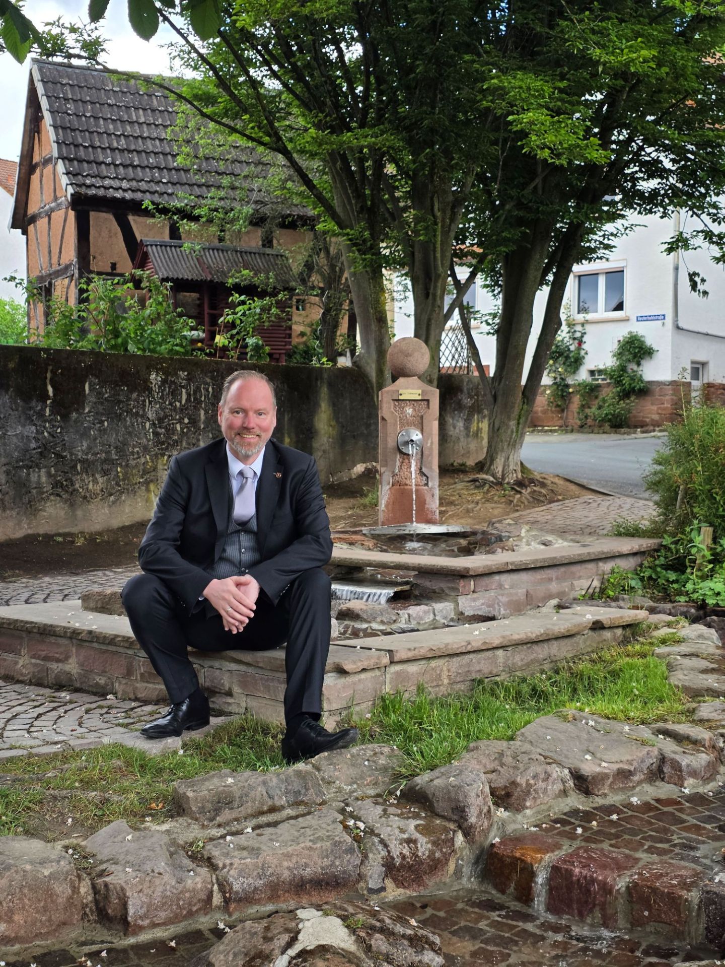 Bürgermeister Christian Litzinger sitzt an der sanierten Brunnenanlage in Roth. 