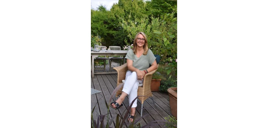 Verena Scheuermann Verena Scheuermann sitzt auf einem Stuhl auf einer Terrasse.