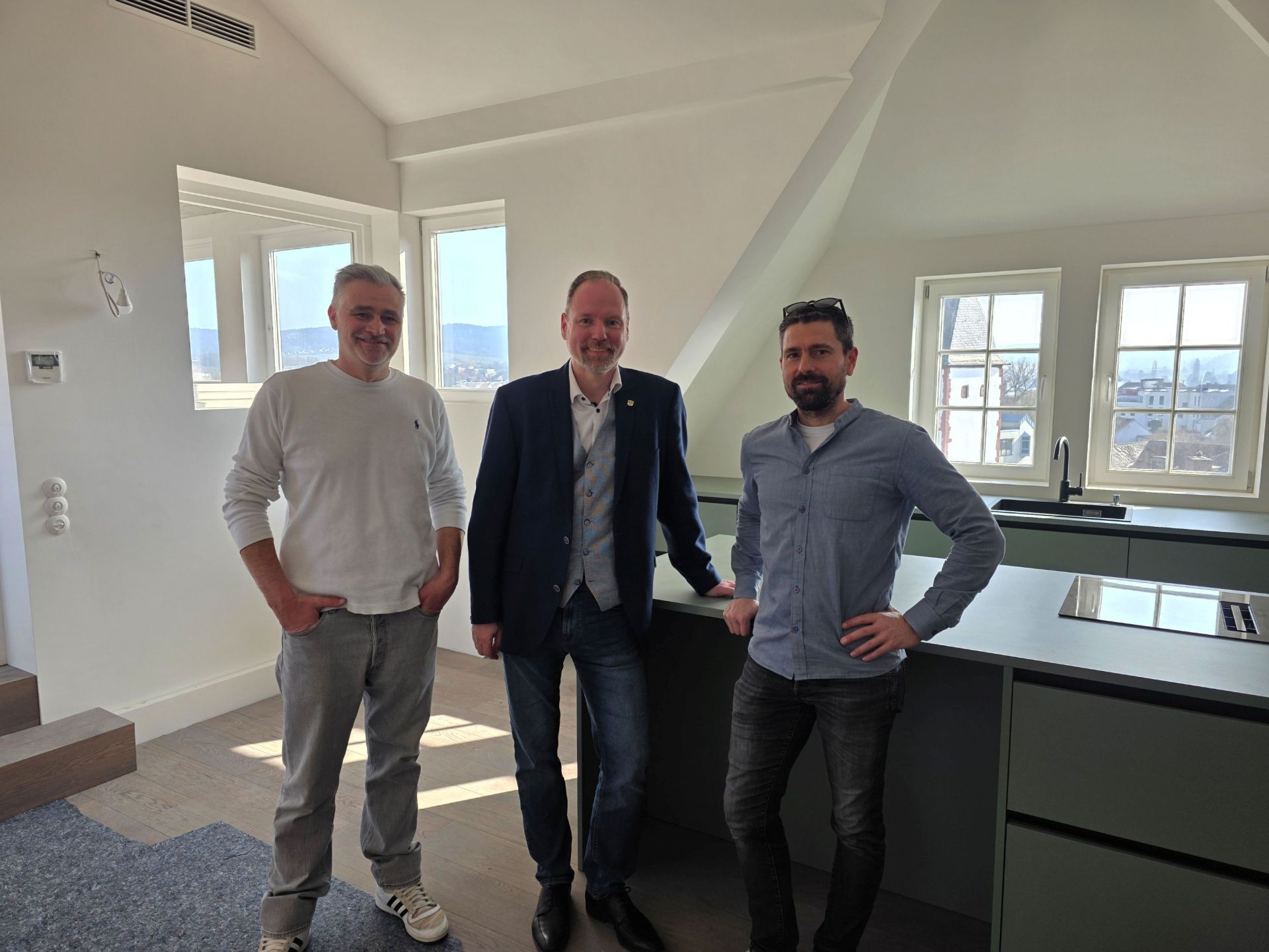 Der Bürgermeister und die zwei Bauherren stehen in der Küche einer neuen Wohnung im Fürstenhof. 
