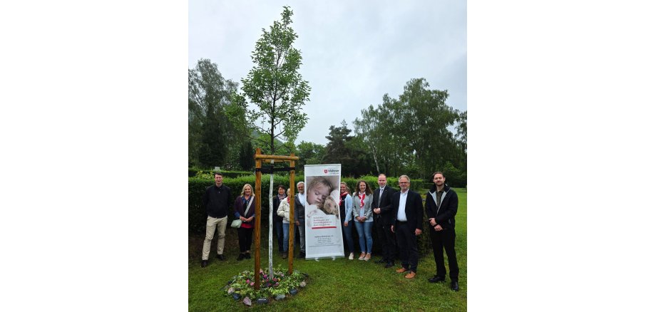 Gedenkbaum Friedhof Gelnhausen Bürgermeister Christian Litzinger und Vertreter der Malteser stehen mit weiteren Teilnehmenden an einem neu gepflanzten Gedenkbaum auf dem Friedhof in Gelnhausen-Mitte und weihen den neuen Gedenkort ein.