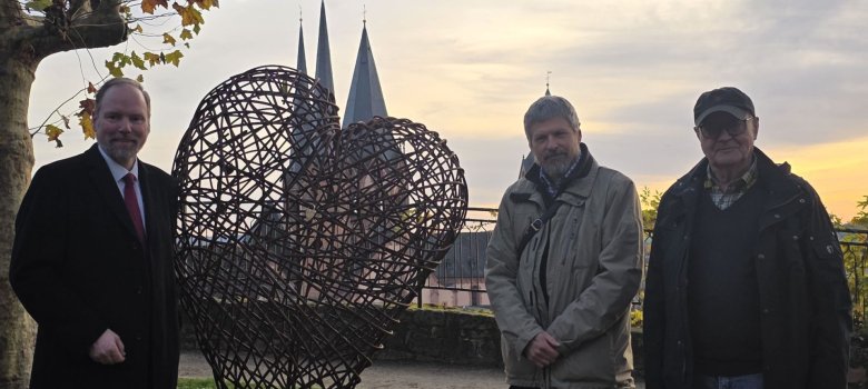 Gelnhausen - Stadt mit Herz (2) Bürgermeister Christian Litzinger, Künstler Faxe Müller und Verkehrsvereinsvorsitzender Heinz Pahlich stehen im Stadtgarten an der neuen Skulptur, die die Form eines Herzes hat.