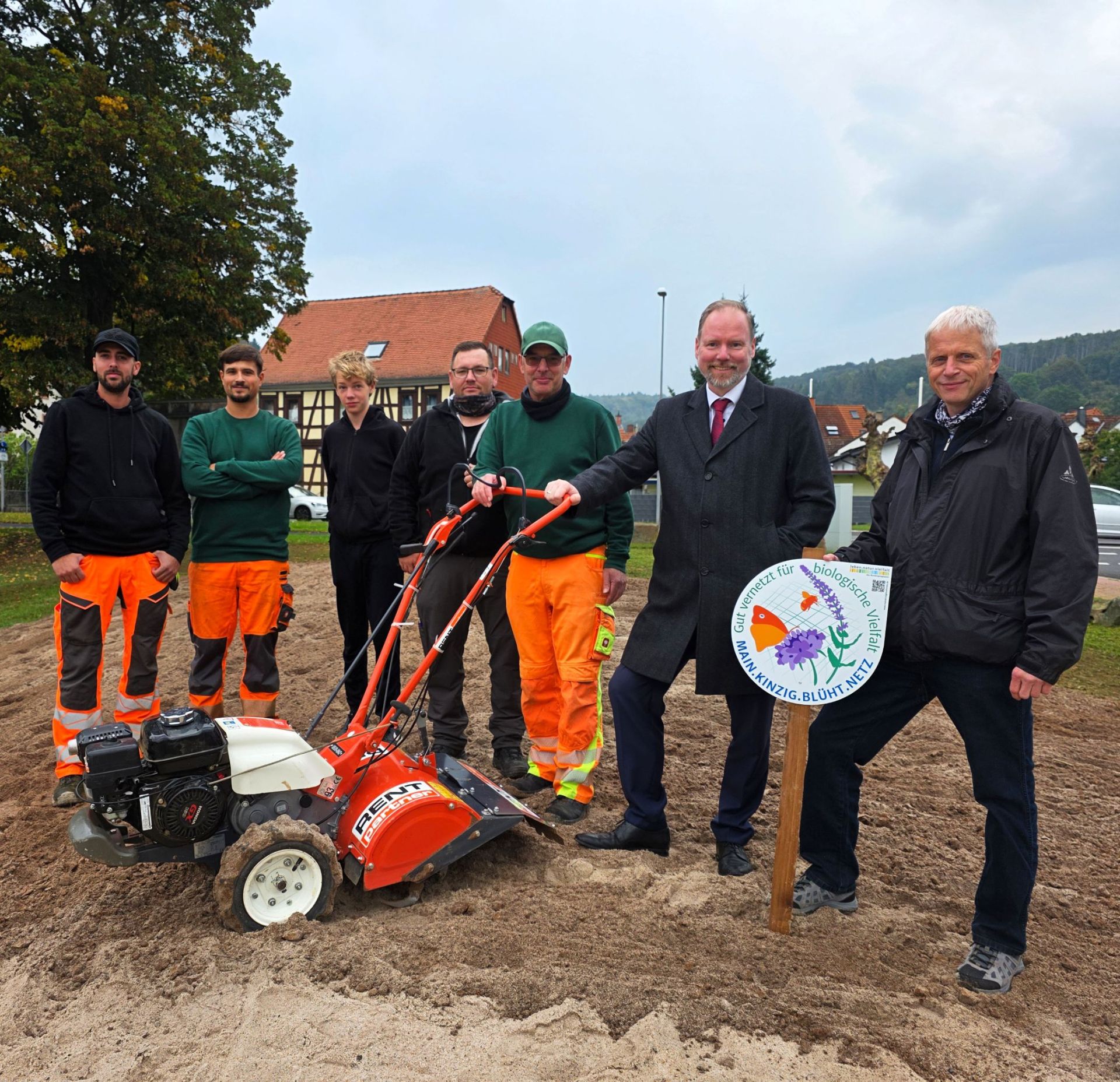 Bürgermeister Christian Litzinger, Umweltberater Jürgen Koch und Mitarbeiter des Betriebshofs stehen auf an einer neuangelegten Blühfläche in Roth. 