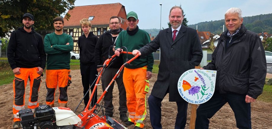 Bürgermeister Christian Litzinger, Umweltberater Jürgen Koch und Mitarbeiter des Betriebshofs stehen auf an einer neuangelegten Blühfläche in Roth. 