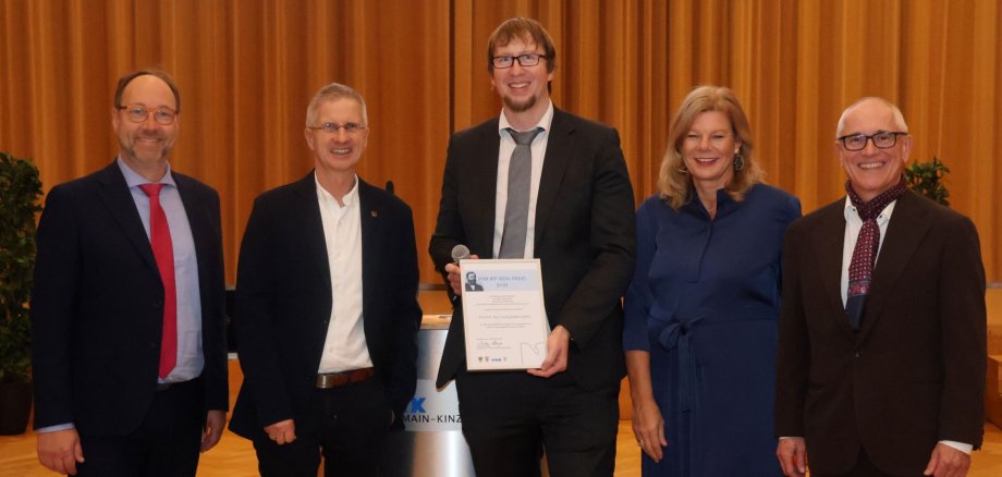 Der Preisträger und die Auszeichnenden stehen gemeinsam im Barbarossasaal des Main-Kinzig-Forums. 