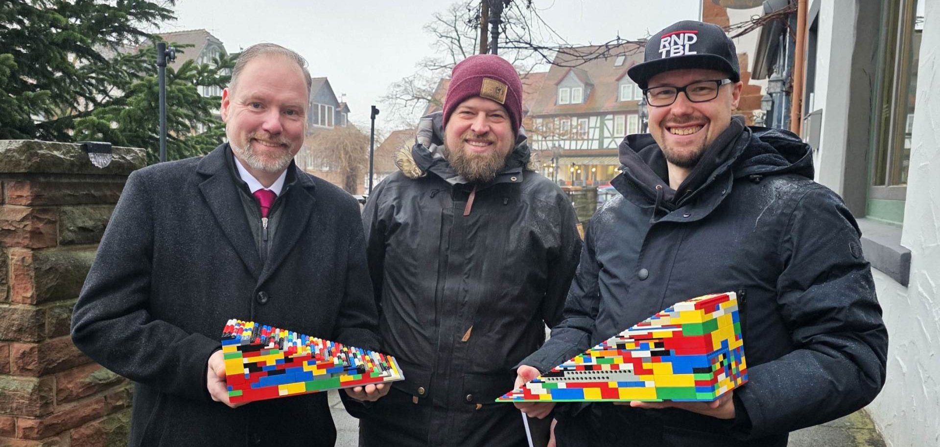 Der Bürgermeister steht mit zwei Männern an der Treppe zur Terrasse am Untermarkt. Die beiden Männer Teile von Legorampen in den Händen. 