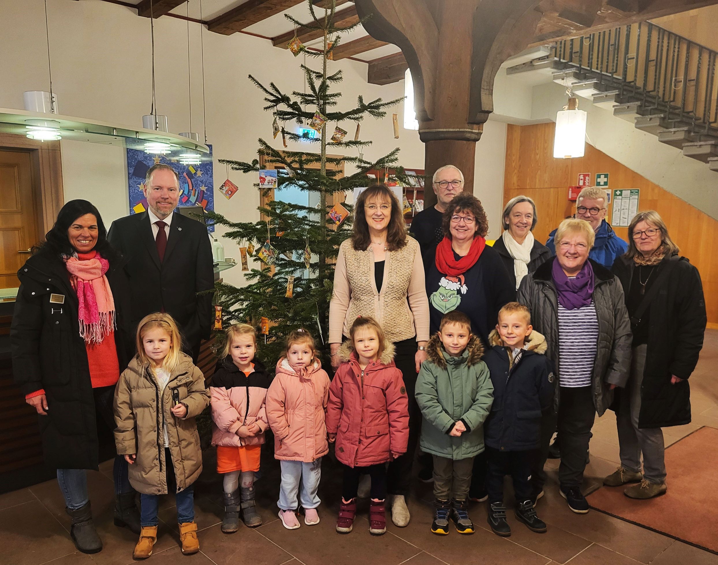 Bürgermeister Christian Litzinger, Mitarbeiter der Stadtverwaltung Gelnhausen und Kinder der Kita "Rappelkiste" mit Kita-Leiterin Kerstin Rott im Rathausfoyer vor dem geschmückten Naschbaum. 