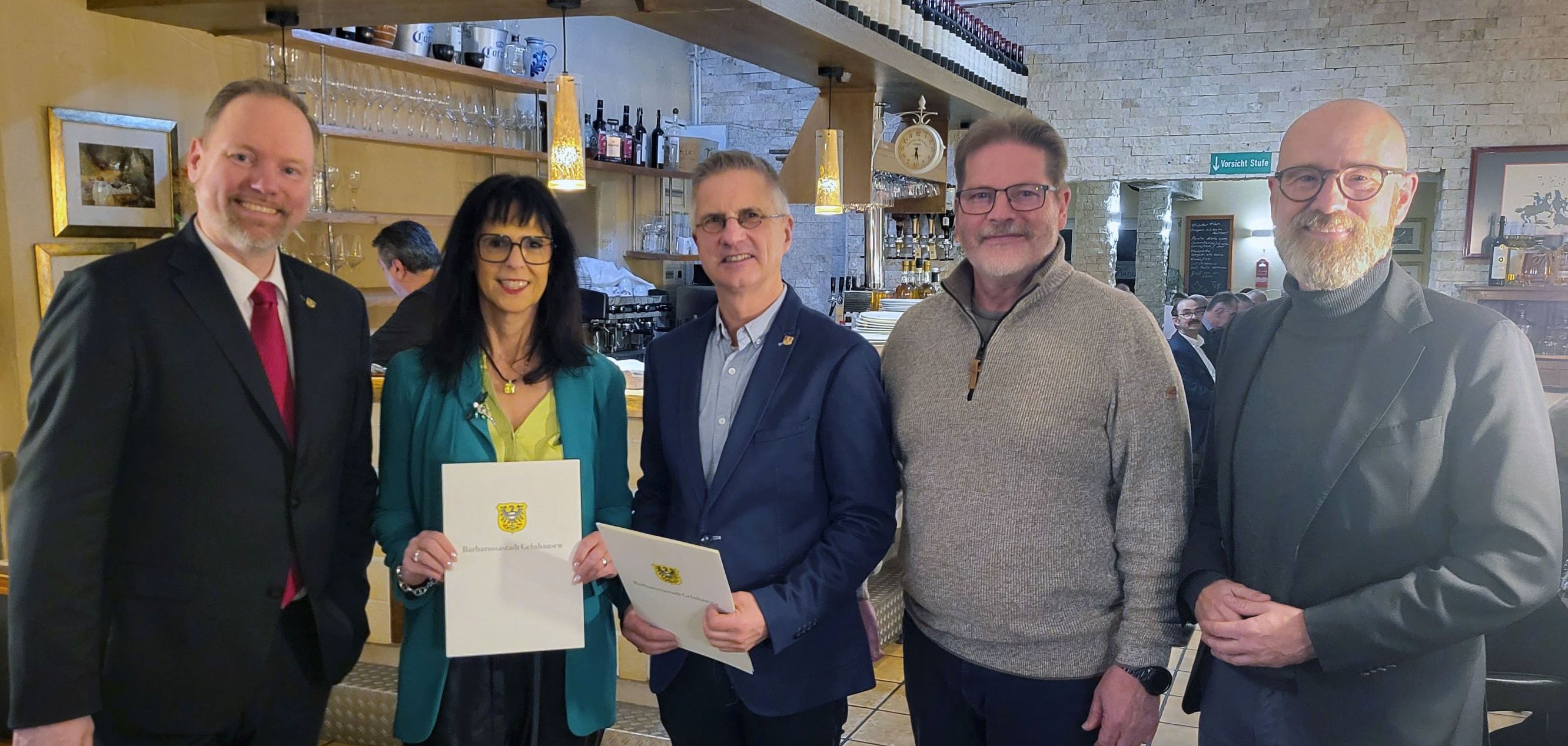 Stadtverordnetenvorsteher Dr. Peter Tauber, Bürgermeister Christian Litzinger und die geehrten Kommunalpolitikerinnen und Kommunalpolitiker stehen gemeinsam in einem Restaurant.