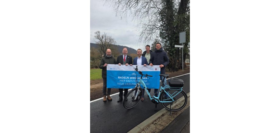 Radweg Clamecystraße Mehrere Personen stehen mit einem Fahrrad und einem Banner in der Hand auf dem neuen Radweg in der Clamecystraße.