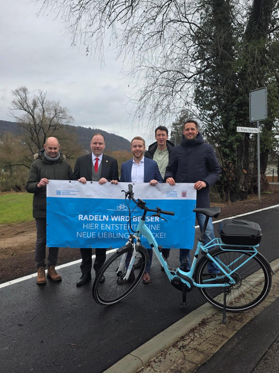Mehrere Personen stehen mit einem Fahrrad und einem Banner in der Hand auf dem neuen Radweg in der Clamecystraße. 