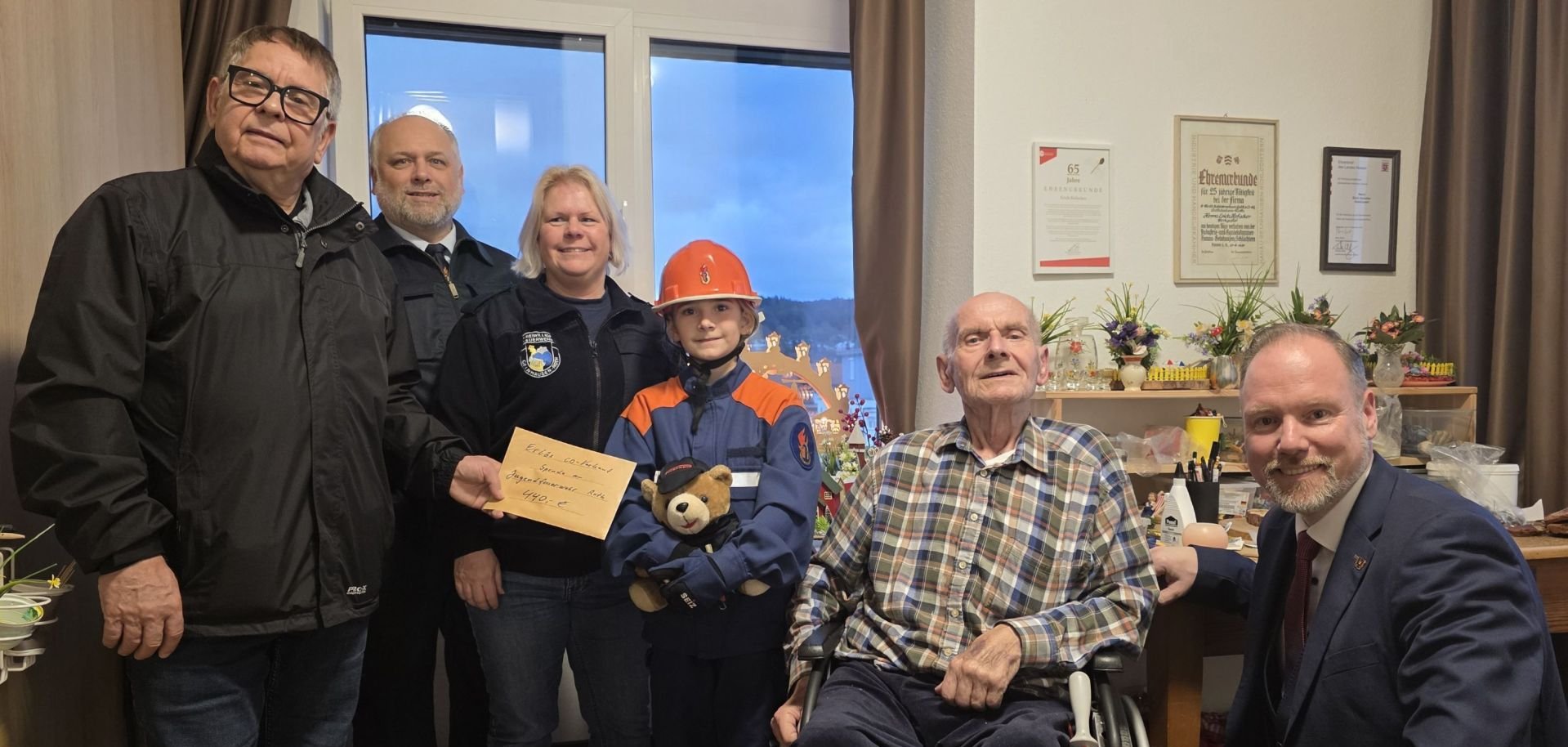 Zwei Männer übergeben eine Spende an Bürgermeister Christian Litzinger und Vertreter der Feuerwehr Roth. 