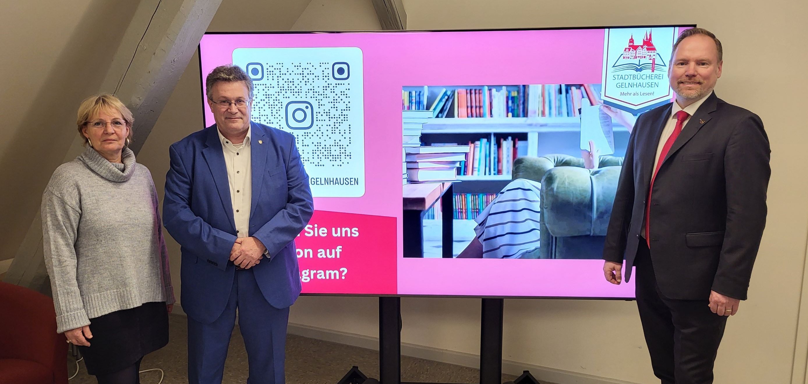 Büchereileiterin Claudia Beck, Landtagsabgeordneter Michael Reul und Bürgermeister Christian Litzinger stehen gemeinsam vor dem neuen Bildschirm in der Stadtbücherei.